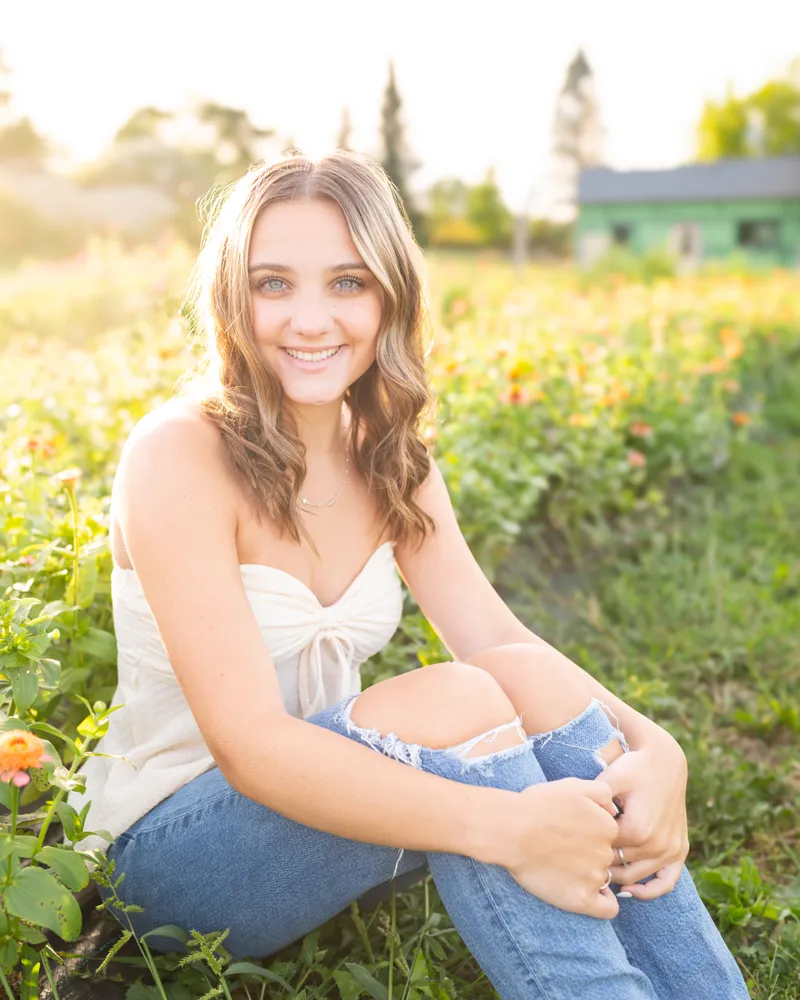 A high school senior standing outdoors among tall grasses during a fall senior portrait session.